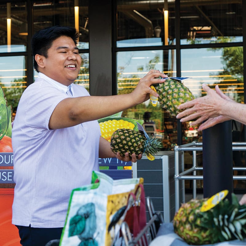 Arvin Batingan, PCC marketing administrator, hands out pineapples to early customers at PCC Burien’s opening.
