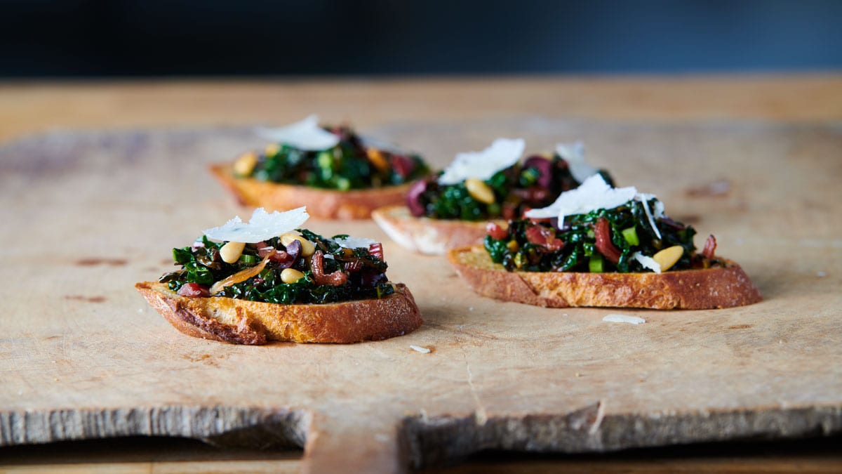 Crostini with Braised Spring Greens, Toasted Pine Nuts and Currants