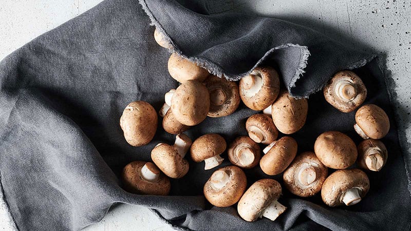 PCC button mushrooms styled on a charcoal colored napkin.