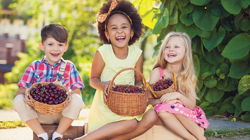 Cute children holding baskets of cherries.