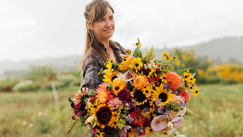 Young farmer holding an enormous bouquet of harvested flowers at Sweet Alyssum Farm. Photo by Rylea Foehl courtesy of Pierce County Fresh.