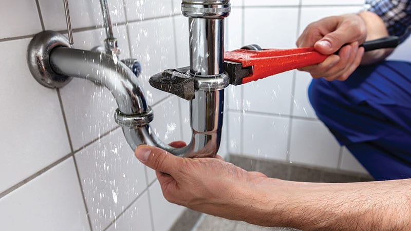 Person fixing a leaky pipe