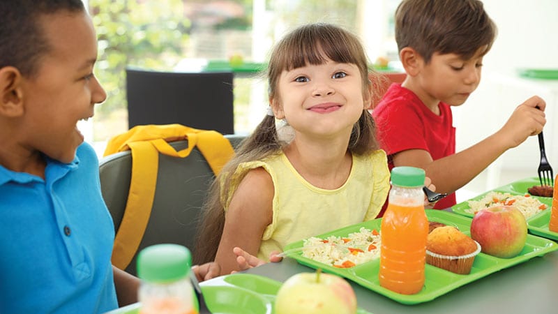 Young children eating healthy school lunch