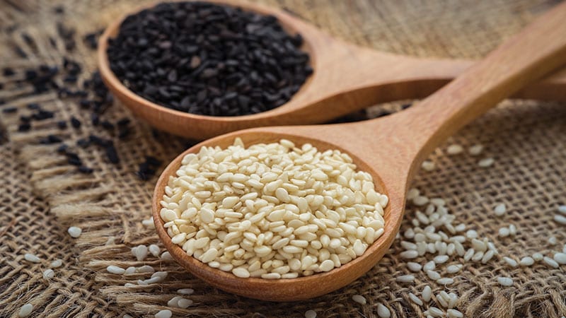 Black and white sesame seeds on wooden spoons