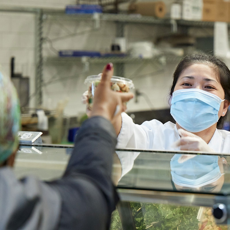 Person wearing mask and hat gardening